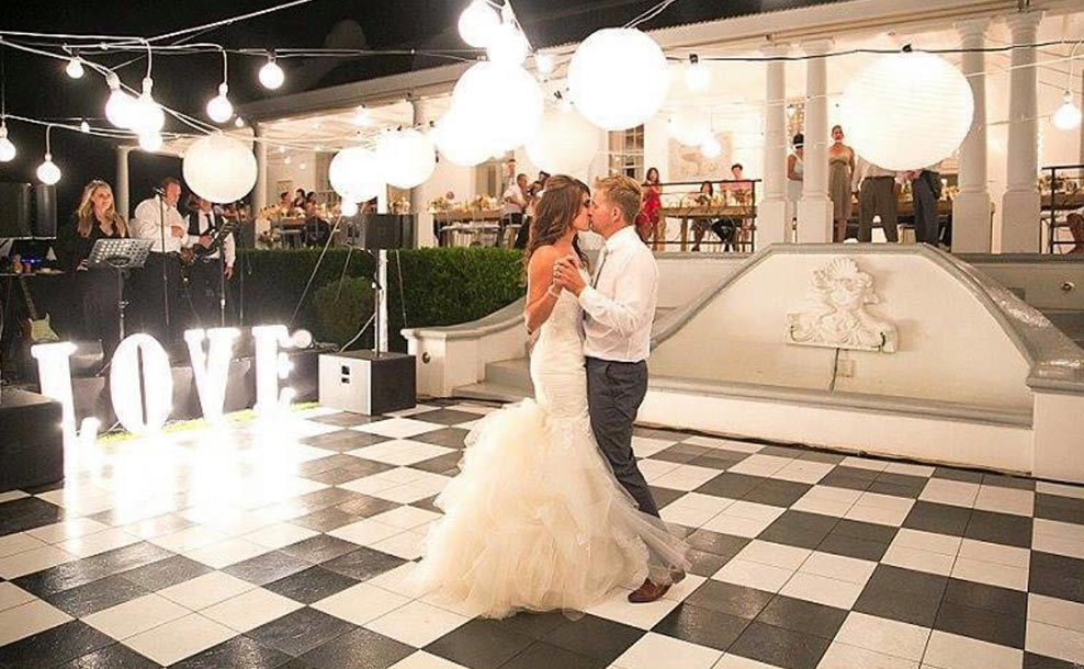 Bride and groom kissing on a checkerboard dance floor