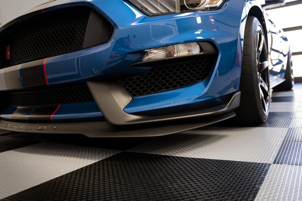 RaceDeck interlocking garage floor tiles installed under a Ford Mustang