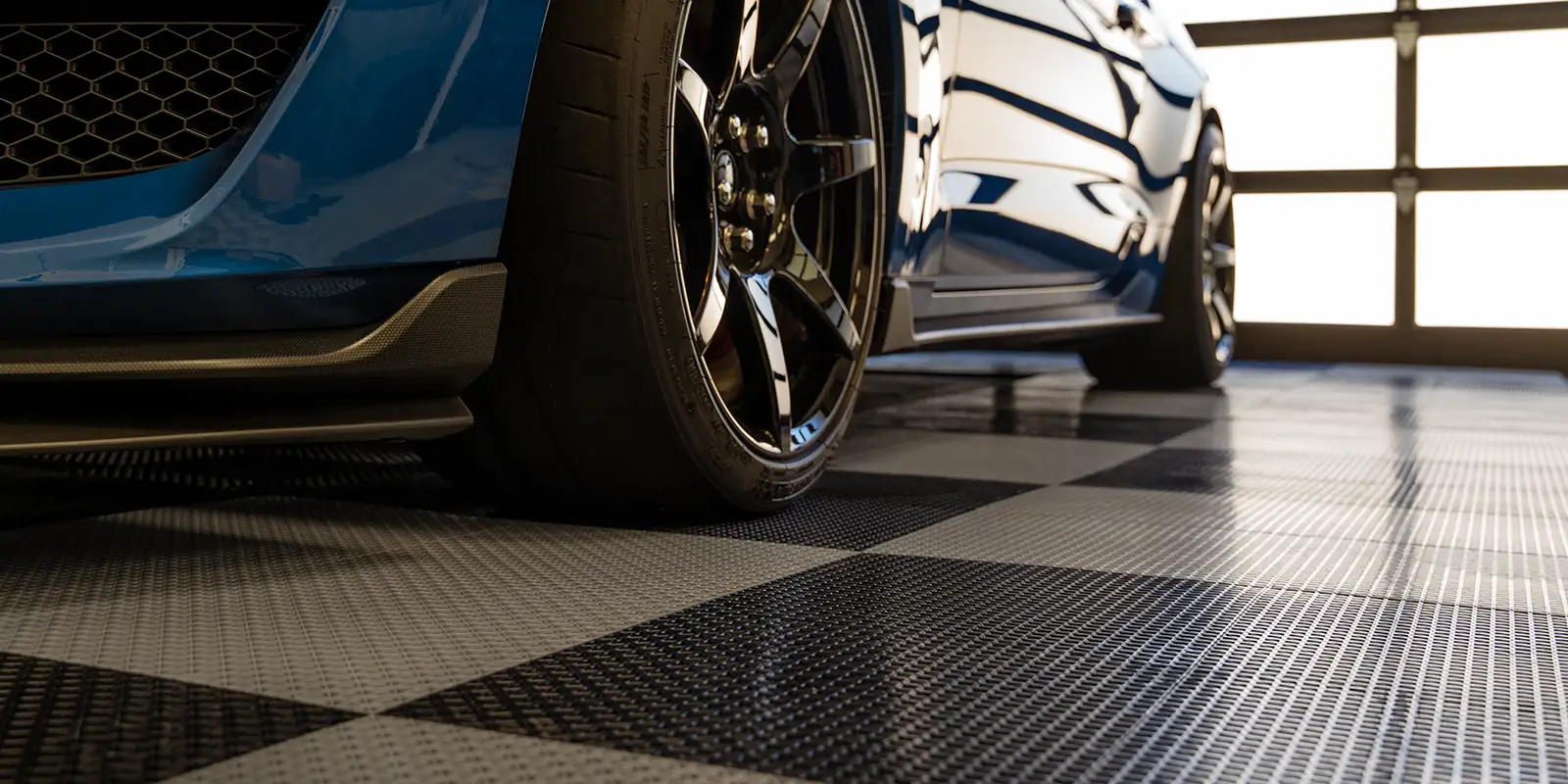 GarageFlow new Mustang parked in a garage with GarageFlow garage flooring tiles.