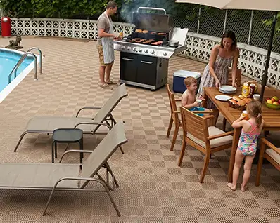 A family is having a bbq on their pool deck. The deck is DuraGrid deck tile